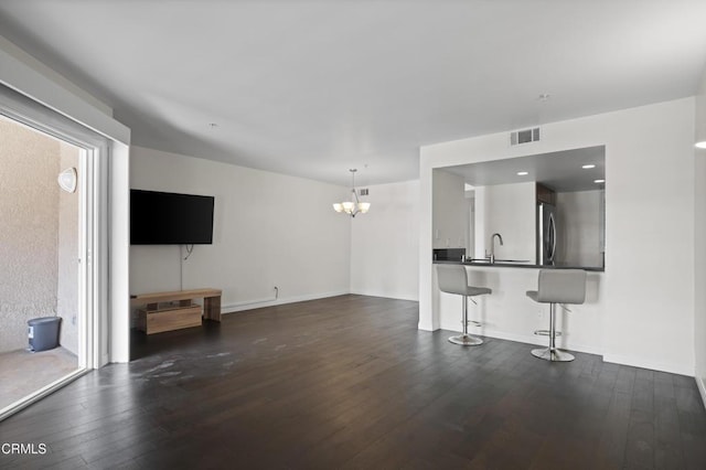 1200 Pacific Coast Hwy Unit 108, Huntington Beach, CA 92648 - unfurnished living room with a notable chandelier, dark wood-style floors, baseboards, and visible vents