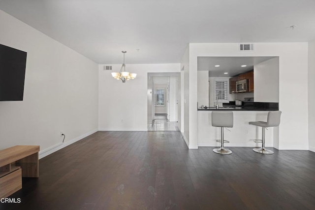 1200 Pacific Coast Hwy Unit 108, Huntington Beach, CA 92648 - unfurnished living room with dark wood finished floors, baseboards, visible vents, and a notable chandelier