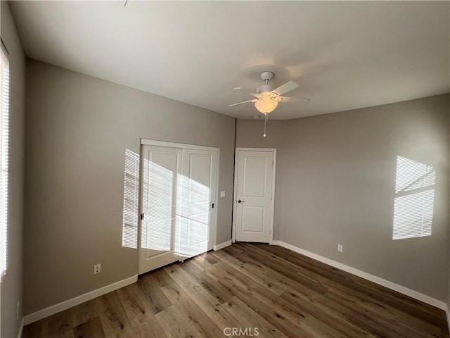 empty room with ceiling fan, plenty of natural light, and wood-type flooring