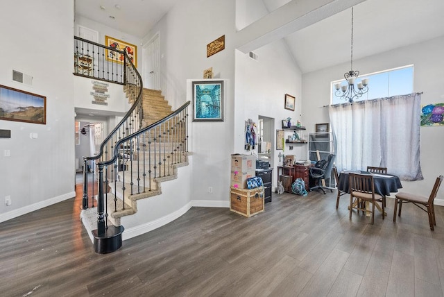 entryway featuring beamed ceiling, hardwood / wood-style floors, a notable chandelier, and a towering ceiling