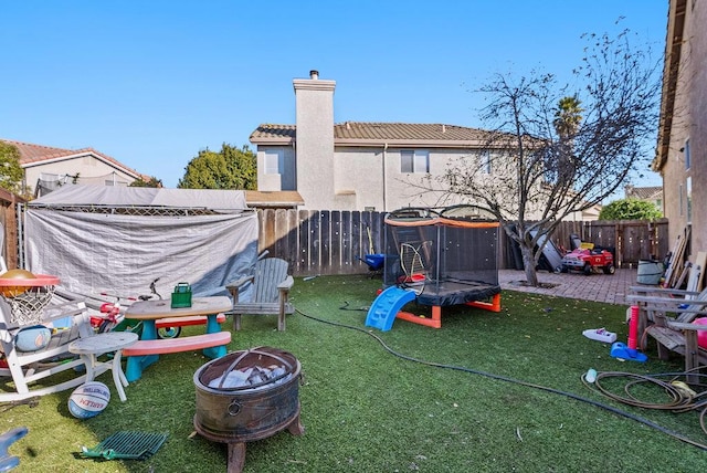 view of yard with a trampoline, a patio, and a fire pit