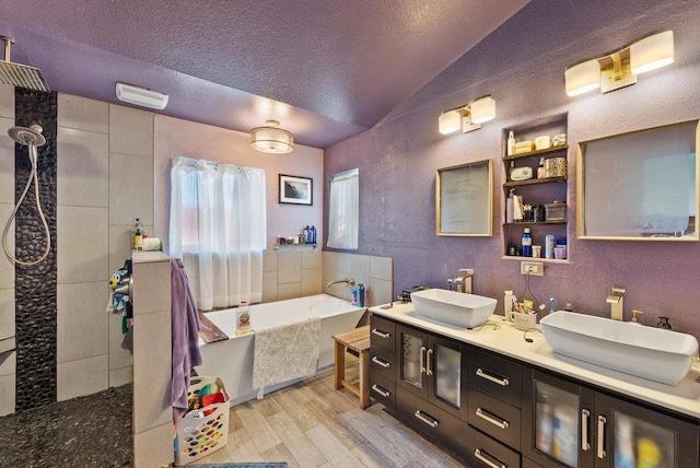 bathroom featuring vanity, vaulted ceiling, hardwood / wood-style flooring, independent shower and bath, and a textured ceiling