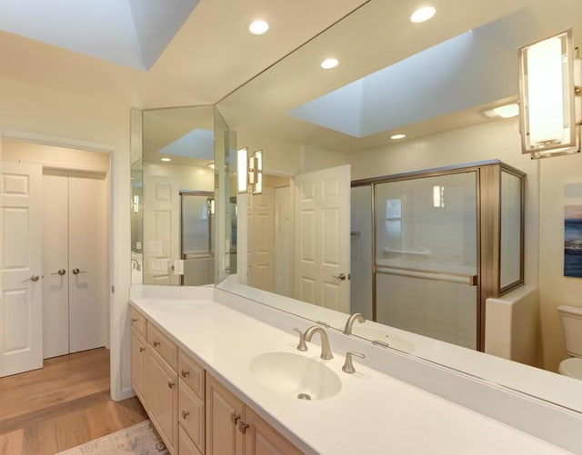 bathroom with vanity, hardwood / wood-style floors, a shower with door, and toilet