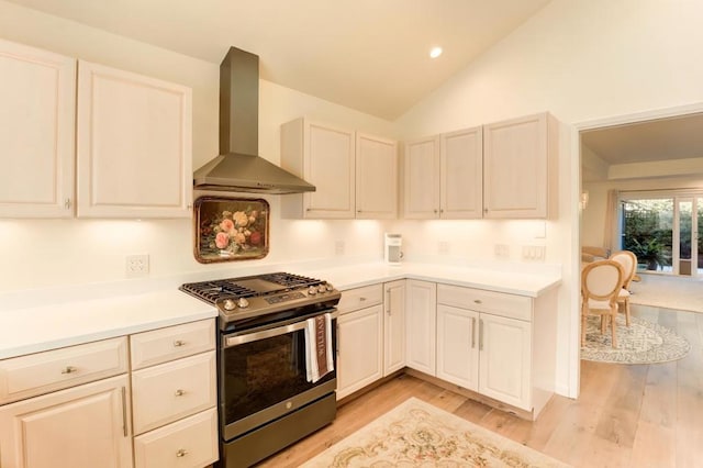 kitchen featuring lofted ceiling, wall chimney range hood, light hardwood / wood-style floors, and stainless steel range with gas stovetop