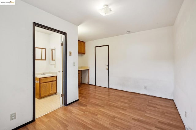 unfurnished bedroom with sink, ensuite bathroom, and light hardwood / wood-style floors