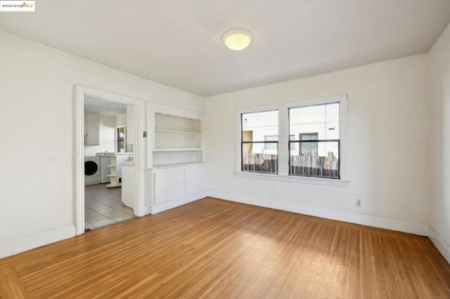 spare room featuring washer / clothes dryer, light hardwood / wood-style floors, and built in features