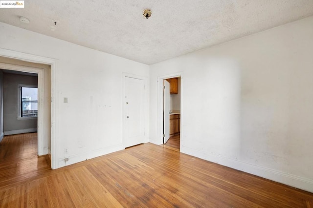 empty room featuring wood-type flooring and a textured ceiling