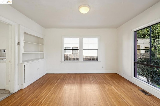 unfurnished room featuring light hardwood / wood-style flooring and built in shelves