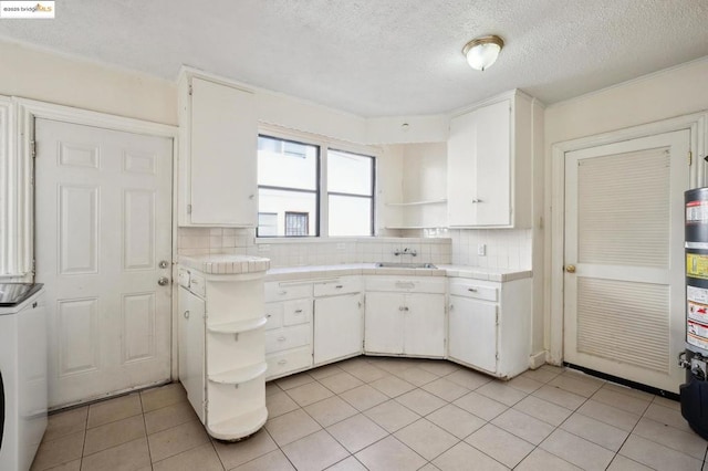 kitchen featuring white cabinets, decorative backsplash, and light tile patterned flooring