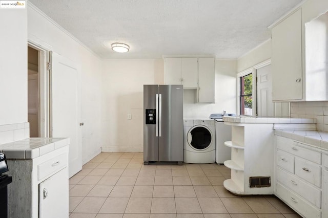 interior space featuring a textured ceiling, washing machine and dryer, light tile patterned flooring, and crown molding