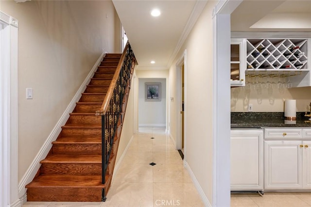 stairs with tile patterned floors, bar, and ornamental molding