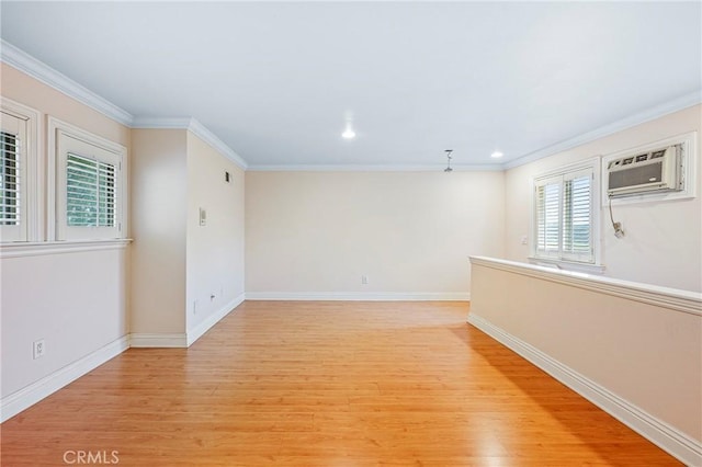 empty room featuring a wall mounted AC, crown molding, and light hardwood / wood-style flooring