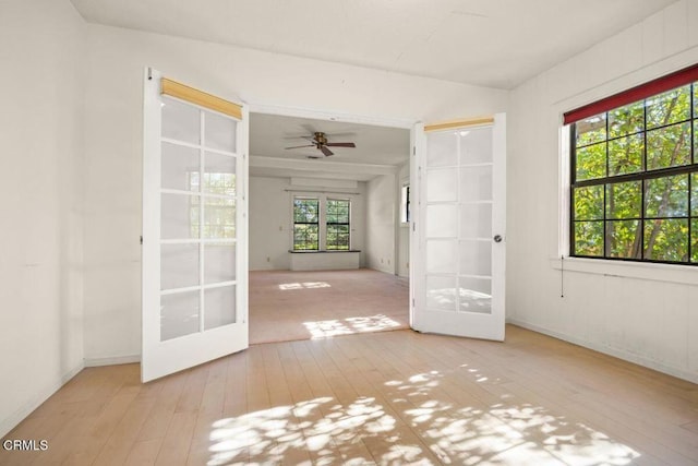 unfurnished room with ceiling fan, light hardwood / wood-style flooring, and french doors