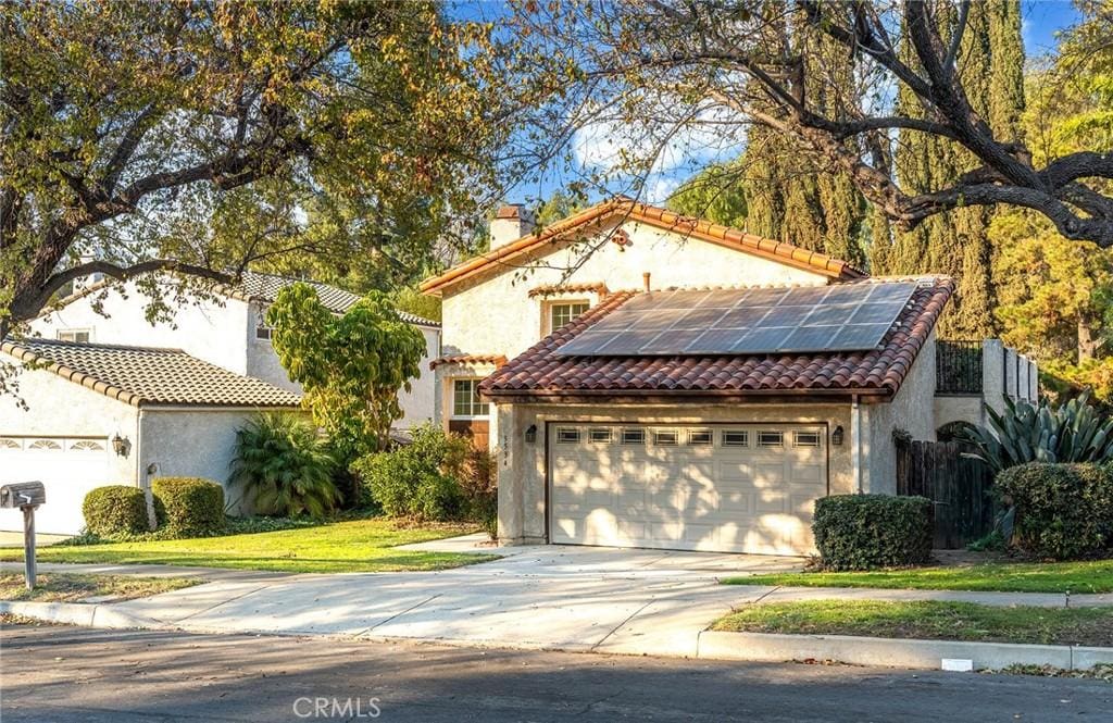 mediterranean / spanish-style home with solar panels and a garage