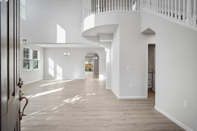 entrance foyer with a towering ceiling, light hardwood / wood-style floors, and a notable chandelier