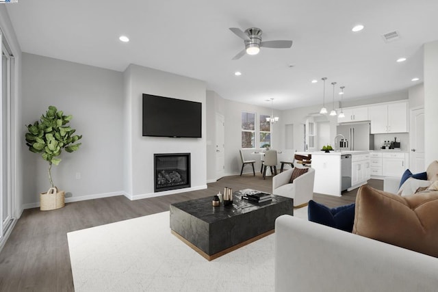 living room with sink, hardwood / wood-style floors, and ceiling fan with notable chandelier