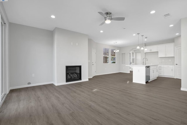 unfurnished living room with sink, dark wood-type flooring, and ceiling fan with notable chandelier