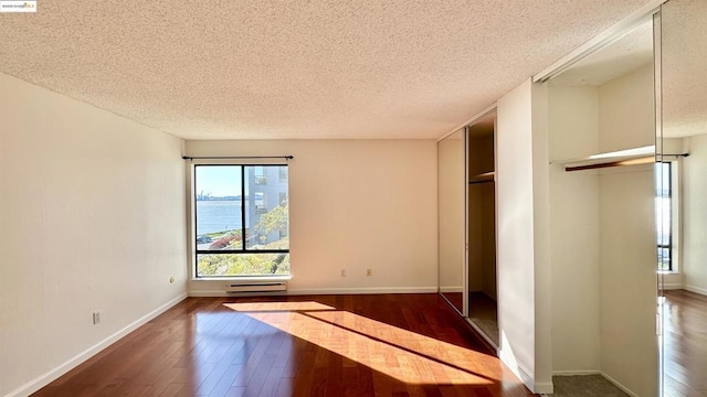 interior space featuring a baseboard radiator, a textured ceiling, multiple windows, and a water view