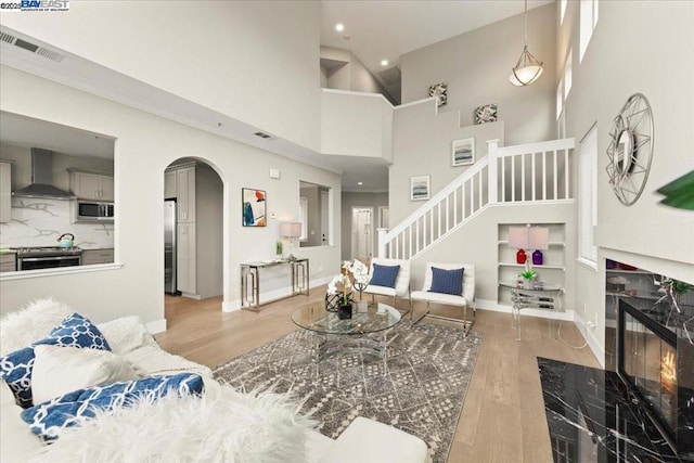 living room with a towering ceiling, a fireplace, and light wood-type flooring