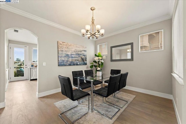 dining area with hardwood / wood-style flooring, a notable chandelier, and crown molding