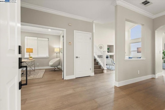 foyer with light hardwood / wood-style floors and crown molding