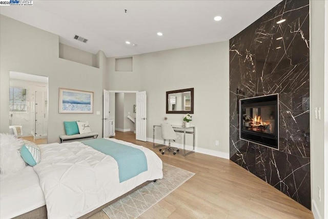 bedroom featuring a premium fireplace and light hardwood / wood-style floors