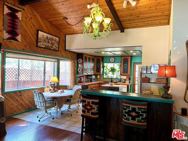 bar with lofted ceiling with beams, a chandelier, light hardwood / wood-style flooring, wood walls, and wooden ceiling