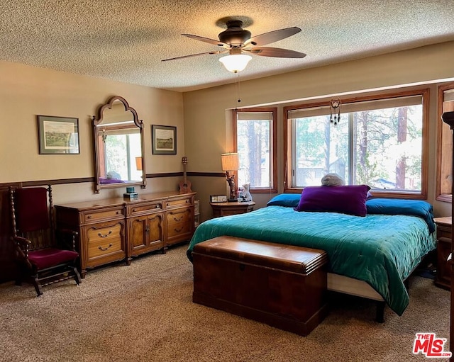 carpeted bedroom featuring ceiling fan and a textured ceiling