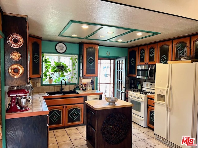 kitchen featuring white appliances, sink, light tile patterned flooring, and a kitchen island