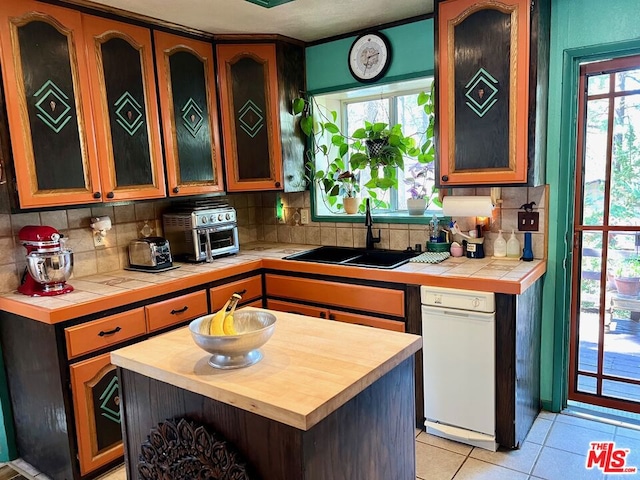 kitchen with backsplash, tile counters, a center island, sink, and light tile patterned flooring