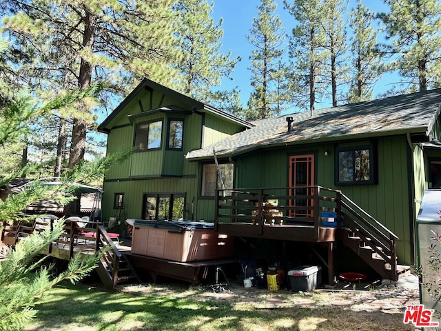 rear view of house with a deck and a hot tub