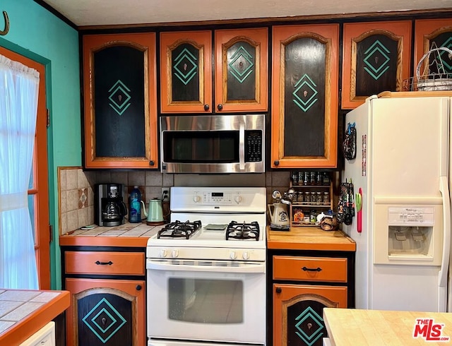 kitchen featuring white appliances, backsplash, and tile counters