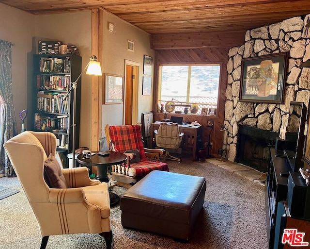 living area featuring vaulted ceiling, wood walls, carpet flooring, wooden ceiling, and a stone fireplace