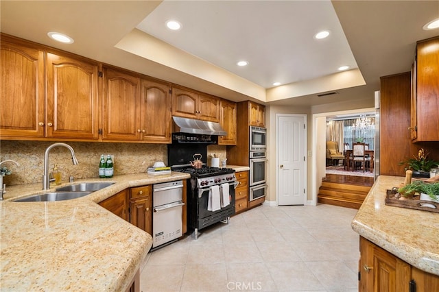 kitchen with sink, a raised ceiling, double oven range, and tasteful backsplash