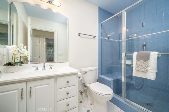 bathroom featuring toilet, vanity, tile patterned floors, and a shower with shower door