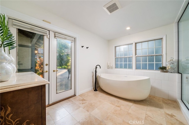 bathroom featuring a washtub, french doors, and vanity