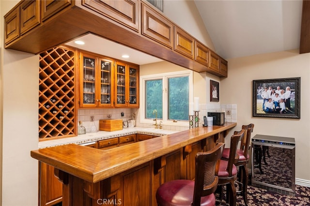 bar with lofted ceiling, butcher block countertops, sink, and backsplash