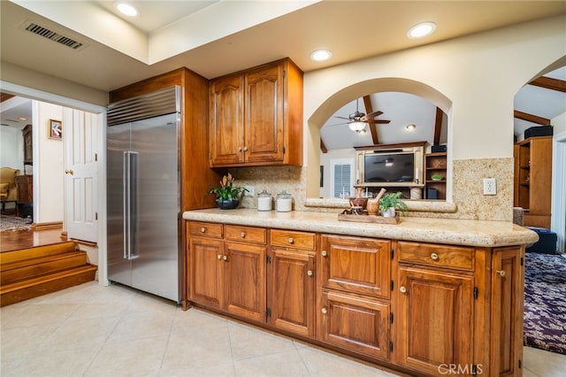 kitchen featuring stainless steel built in refrigerator, decorative backsplash, ceiling fan, and kitchen peninsula