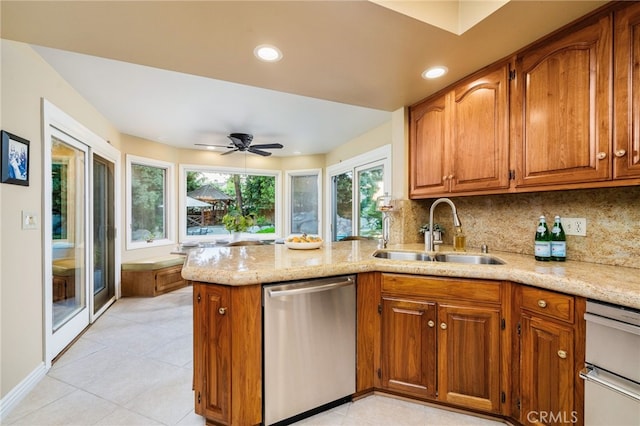 kitchen featuring light stone countertops, ceiling fan, sink, stainless steel dishwasher, and tasteful backsplash