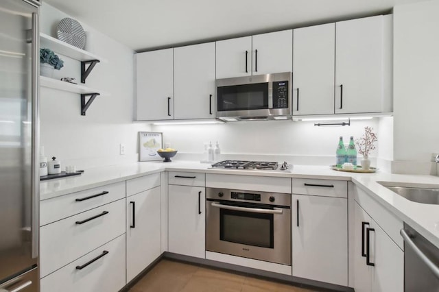 kitchen with appliances with stainless steel finishes, dark tile patterned floors, sink, and white cabinets