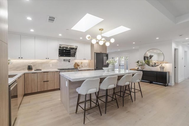 kitchen featuring white cabinets, a skylight, fridge, and a kitchen island