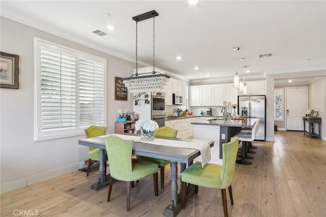 dining area featuring crown molding, sink, and light wood-type flooring