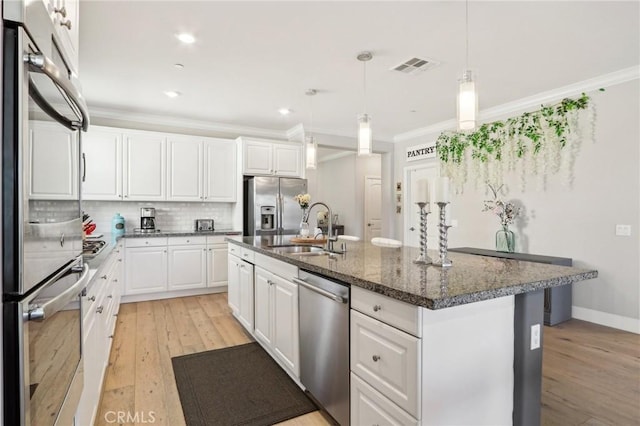 kitchen with white cabinetry, appliances with stainless steel finishes, a center island with sink, and sink