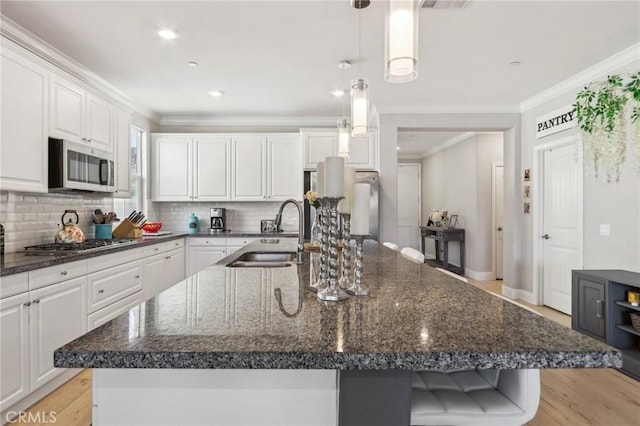 kitchen with white cabinetry, appliances with stainless steel finishes, a kitchen island with sink, and sink