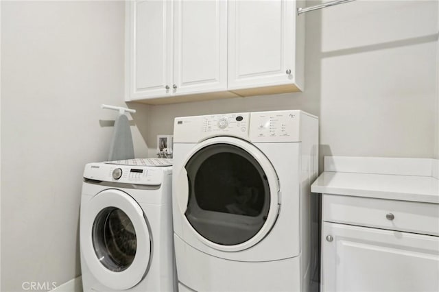 laundry room with washing machine and dryer and cabinets