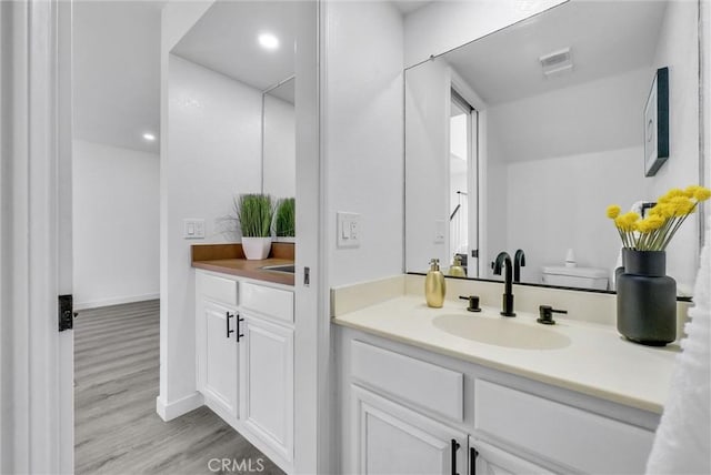 bathroom with toilet, vanity, and hardwood / wood-style flooring