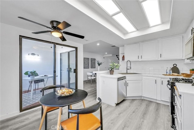 kitchen with dishwasher, white cabinets, range with gas stovetop, kitchen peninsula, and sink