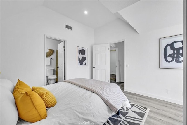 bedroom with connected bathroom, lofted ceiling, and wood-type flooring