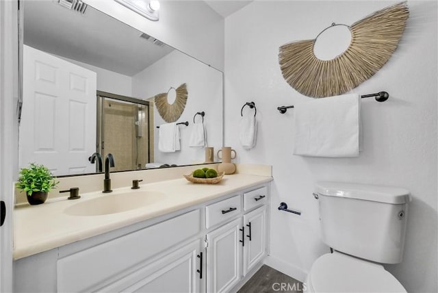 bathroom with toilet, a shower with door, and vanity