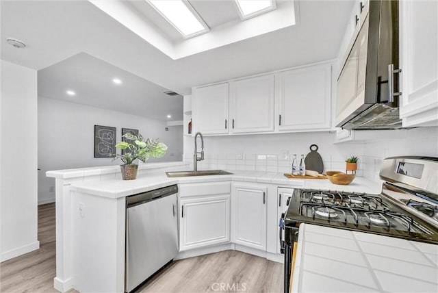 kitchen with stainless steel appliances, white cabinets, sink, and kitchen peninsula